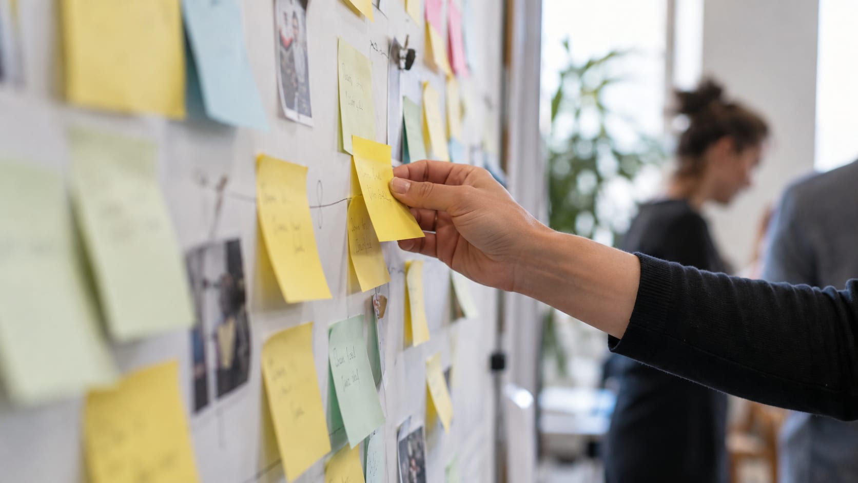 Main déplaçant un post-it lors d’un atelier collaboratif en équipe.